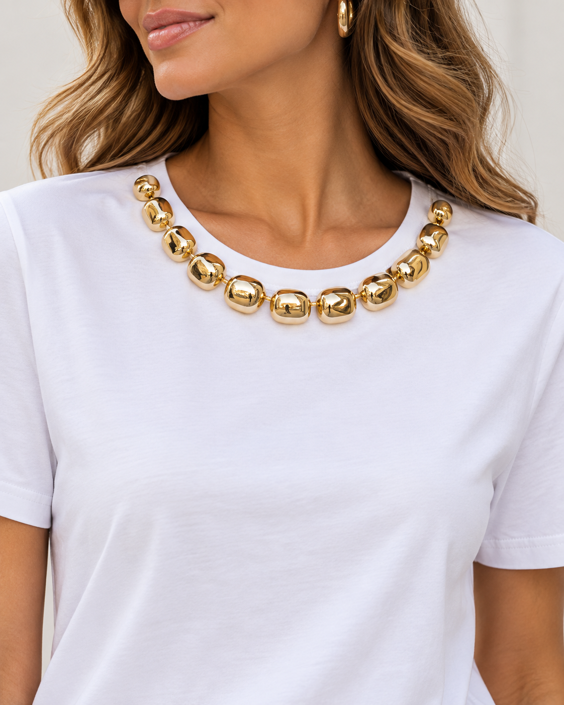 Detalle del escote de la camiseta blanca con adornos dorados
