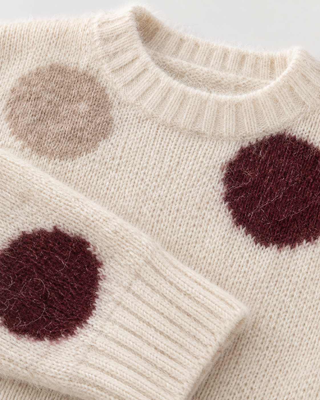 Detalle de punto y lunares del jersey crema