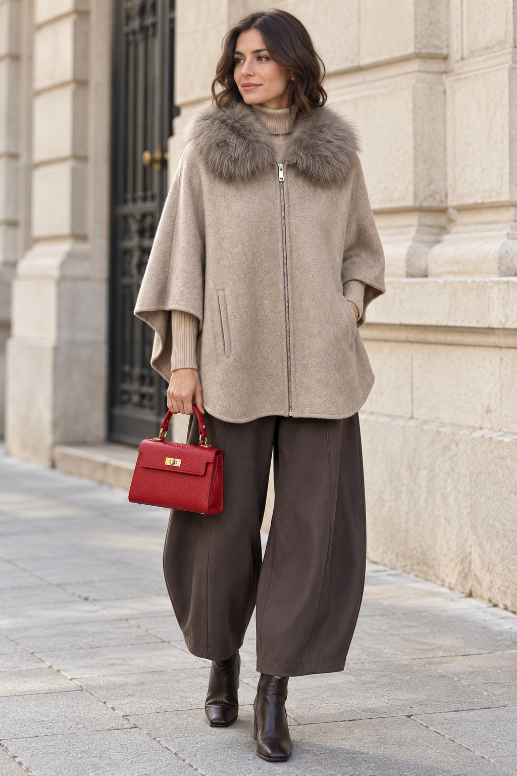 Capa topo con cuello de pelo y cremallera, combinada con jersey beige, pantalón de pernera curva y bolso rojo