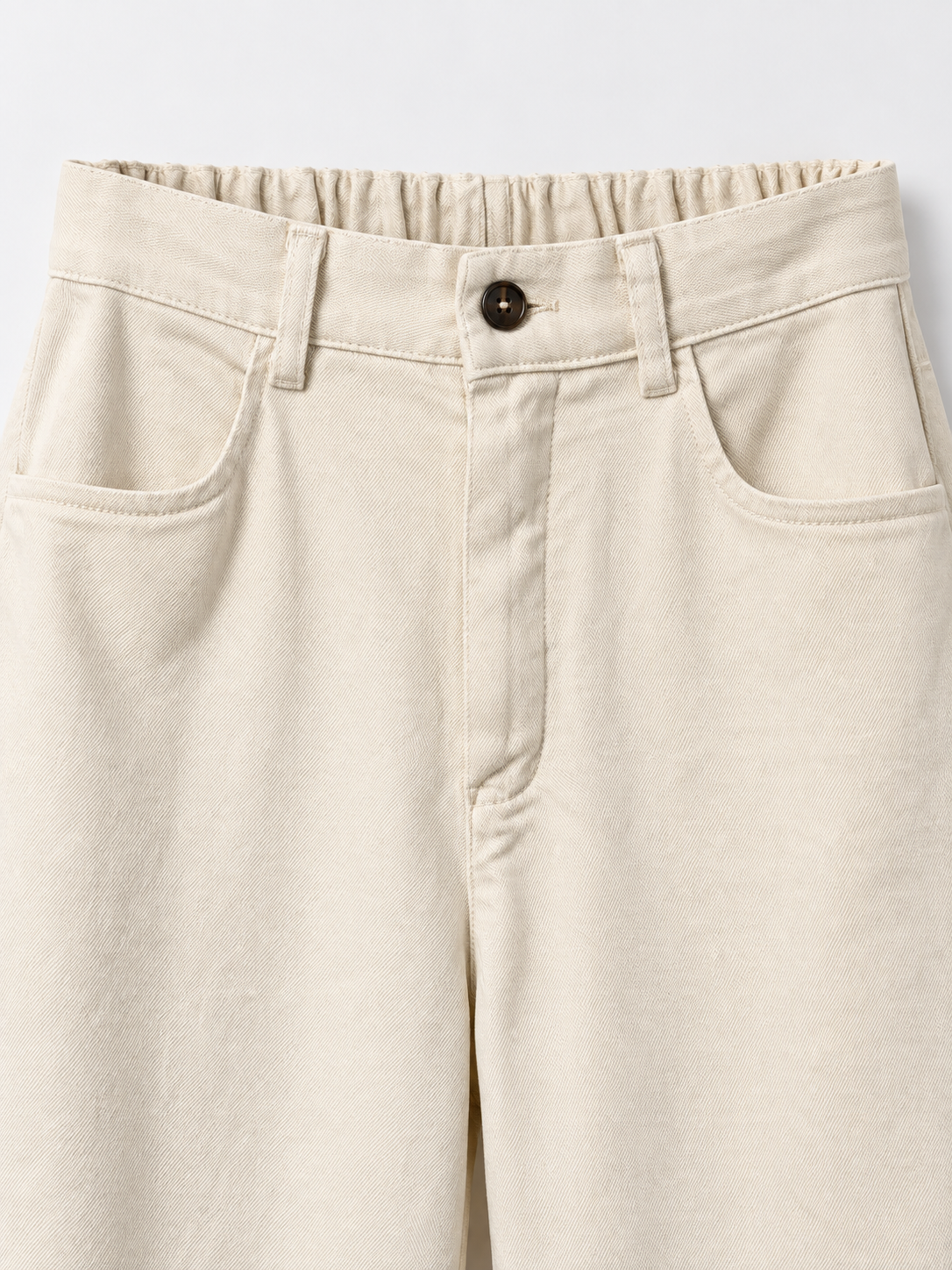 Cintura, botón y bolsillos del pantalón beige
