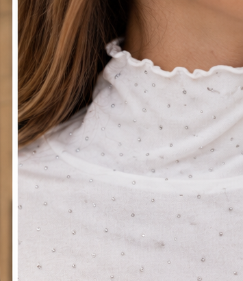 Detalle del cuello alto y brillos del top blanco